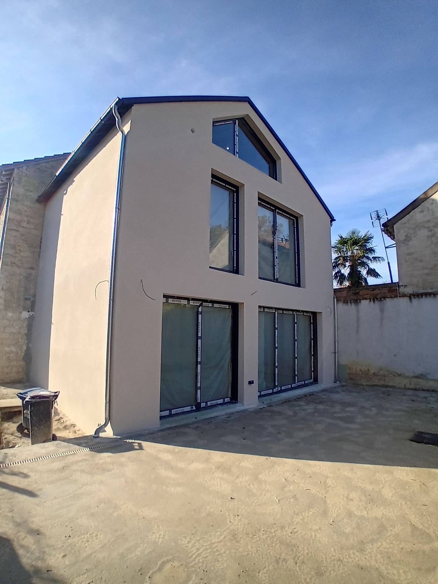 Façade sur jardin enduite, grandes baies et pignon